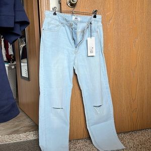 High rise mom jeans, light blue color, ripped at the knee.